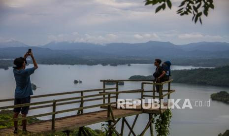 Pengunjung berfoto dengan latar belakang Pegunungan Meratus di kawasan Geopark Meratus wisata Bukit Batas di Desa Tiwingan Baru, Kabupaten Banjar, Kalimantan Selatan, Ahad (13/3/2022). Wisata Bukit Batas menjadi salah satu obyek wisata favorit di Kalimantan Selatan yang menawarkan keindahan alam Pegunungan Meratus dan pemandangan gugusan pulau-pulau kecil yang berada di kawasan Waduk Riam Kanan.