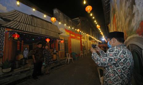 Pengunjung berfoto di depan salah satu mural bernuansa Tionghoa saat peluncuran awal Wisata Kampung Pecinan di Jalan Kapasan Dalam, Surabaya, Jawa Timur, Selasa (10/11/2020). Kawasan yang juga merupakan salah satu kampung pecinan tertua di Surabaya tersebut diharapkan dapat menjadi destinasi wisata baru berkonsep kampung dengan menyuguhkan bangunan-bangunan bersejarah, pusat kuliner khas Tionghoa, spot foto yang menarik dan pertunjukan seni seperti barongsai dan wayang potehi.