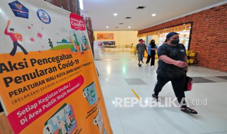 Pengunjung bergegas keluar di samping poster imbauan pencegahan penularan COVID-19 di pusat berbelanjaan modern, Jambi, Senin (12/7/2021). Pemerintah Kota Jambi membatasi jam operasional pusat perbelanjaan atau perdagangan di daerah itu sampai pukul 17.00 WIB dengan pembatasan kapasitas pengunjung 25 persen dan penerapan protokol kesehatan untuk mengendalikan penyebaran COVID-19. 