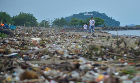 Pengunjung berjalan di antara sampah yang berserakan di Pantai Padang, Sumatera Barat, Senin (18/4/2022). Intensitas curah hujan yang tinggi dua hari terakhir di kota itu membuat sampah-sampah dari hulu terbawa aliran sungai hingga ke laut dan terdampar ke pantai. 