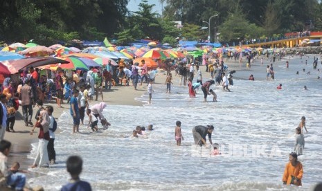 Pengunjung bermain ombak di Pantai Gandoriah, Pariaman, Sumatra Barat. 