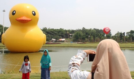 Pengunjung berpose foto dengan latar belakang patung bebek raksasa disela acara peluncuran Giant Yellow Duck, di Central Park Meikarta, Cikarang, Kabupaten Bekasi, Jawa Barat, Minggu (5/11). 