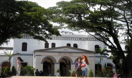 Pengunjung berswafoto dengan latar bangunan tua Stasiun Bogor saat wisata di Alun-Alun Kota Bogor, Jawa Barat, Sabtu (18/12/2021). Alun-Alun Kota Bogor yang memiliki fasilitas lintasan lari, alat fitnes dan wahana permainan anak tersebut menjadi destinasi wisata baru dalam mengisi libur akhir pekan. 