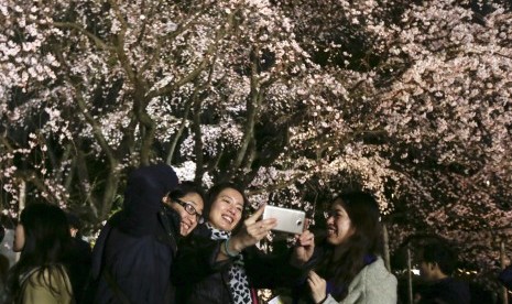 Pengunjung berswafoto dengan latar bunga sakura yang mekar di Rikugien Garden Tokyo, (27/3). Pengelola taman menyebut sudah 30 ribu orang datang untuk melihat bunga sakura.