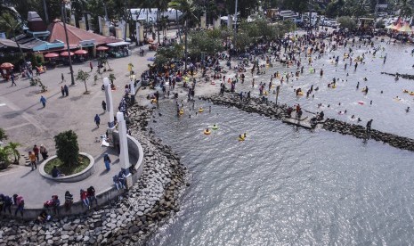 Pengunjung dari berbagai daerah memadati Pantai Festival Taman Impian Jaya Ancol, Jakarta, Senin (26/12).