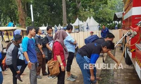 Pengunjung GBK berwudhu dari air truk pemadam kebakaran. Kamis (30/8).