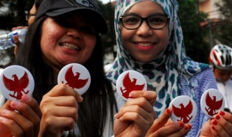 Pengunjung kegiatan Hari Tanpa Kendaraan Bermotor memerlihatkan pin Garuda untuk dukungan pasangan Prabowo-Hatta, Bandung, Jawa Barat, Ahad (15/6).