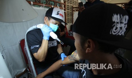 Pengunjung melakukan hapus tato di Hijrah Care pada acara Muhasabah Akhir Tahun Republika 2018, di Selasar Masjid Pusdai, Kota Bandung, Senin (31/12). 