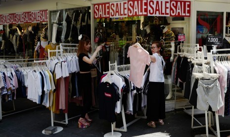 Pengunjung melihat-lihat pakaian yang dijual di kawasan Myeong-dong, Seoul, Korea Selatan.