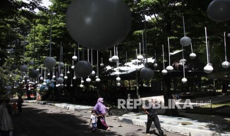 Pengunjung melintas di bawah dekorasi berbahan bola plastik di Taman Satwa Taru Jurug (TSTJ) Solo, Jawa Tengah, Rabu (29/12/2021). Selain sebagai daya tarik wisata bagi pengunjung, dekorasi tersebut dibuat untuk memeriahkan dan mendukung timnas sepak bola Indonesia pada ajang final Piala AFF 2020 di Singapura. 