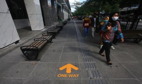 Pengunjung melintas di dekat tanda jaga jarak dan jalan satu arah di Kawasan Wisata Malioboro, Yogyakarta, Kamis (18/6/2020). Sebagai salah satu persiapan menghadapi tatanan normal baru saat pandemi COVID-19, kawasan wisata Malioboro menerapkan protokol kesehatan bagi pengunjung seperti wajib penggunaa masker, pengukuran suhu tubuh, scan barcode data diri pengunjung, wajib cuci tangan hingga pemasangan tanda jaga jarak dan jalan satu arah. 