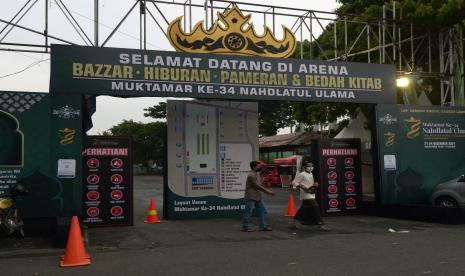 Pengunjung melintas di depan gapura pintu masuk Bazar, hiburan, dan pameran di Lapangan Saburai, Bandar Lampung, Lampung, Selasa (21/12/2021). Kegiatan bazar, pameran, hiburan, dan bedah kitab merupakan rangkaian dari acara Muktamar NU ke-34 di Provinsi Lampung.