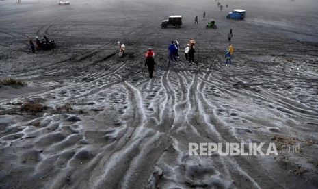 Pengunjung melintas di hamparan pasir yang diselimuti embun upas di kawasan Gunung Bromo, Probolinggo, Jawa Timur, Ahad (3/6/2023). 