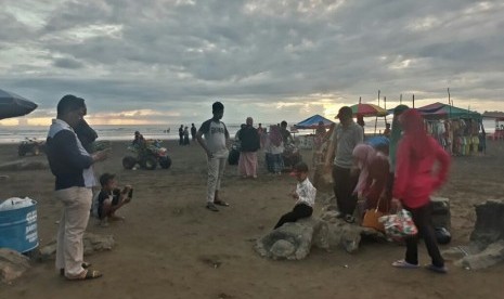   Pengunjung memadati Pantai Air Manis di Kota Padang, Sumatra Barat, Ahad (31/12). Destinasi wisata Pantai Air Manis juga terkenal dengan batu Malin Kundang. 