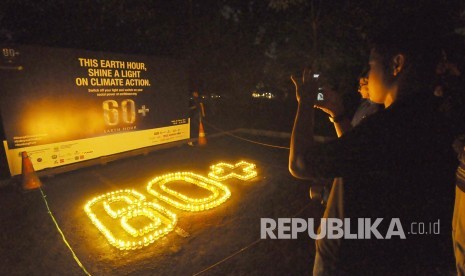 Pengunjung memfoto lilin yang membentuk 60+ saat acara Earth Hour di parkiran barat Gedung sate, Kota Bandung, Sabtu (25/3) malam. kegiatan Earth Hour tersebut merupakan kampanye mengajak untuk lebih menghemat energi 