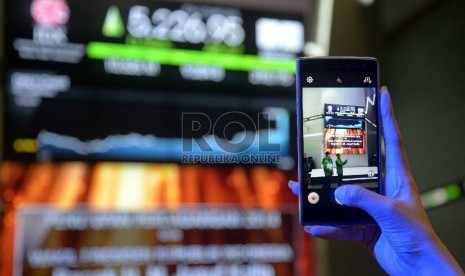  Pengunjung memotret tabel perdagangan saham saat penutupan perdagangan saham di Bursa Efek Indonesia (BEI).