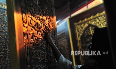 Pengunjung memperhatikan ukiran Alquran dari kayu trembesi di kawasan Bait Al Quran rakasasa Al Akbar Gandus Palembang, Sumatera Selatan, Senin (21/5). 