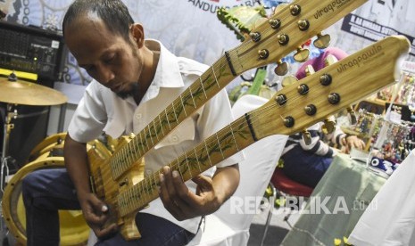 Pengunjung mencoba alat musik gitar berbahan bambu di Virageawie Indonesia pada Pameran UMKM di area Komplek Perkantoran Pemda Kabupaten Bandung Barat, Rabu (19/6).