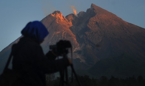 Pengunjung mengabadikan puncak Gunung Merapi yang mengeluarkan asap putih dari kawasan Balerante, Kemalang, Klaten, Jawa Tengah, Senin (7/1/2019).