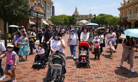 Pengunjung mengenakan masker berjalan di Hong Kong Disneyland, Kamis 21 April 2022. Hong Kong Disneyland dibuka kembali untuk umum setelah ditutup akibat lonjakan infeksi COVID-19.