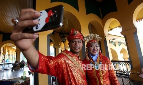 Pengunjung mengenakan pakaian adat melayu berfoto di dalam Istana Maimun, Medan, Sumatera Utara, Kamis (28/4).Republika/Rakhmawaty La'lang