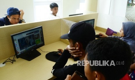   Pengunjung menikmati internet Perpustakaan Gasibu, di kawasan Lapangan Gasibu, Kota Bandung, Ahad (18/9). 