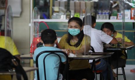 Pengunjung menikmati makanan di meja makan yang bersekat di pusat jajanan serba ada (pujasera) atau food court Pasar Atom, Surabaya, Jawa Timur, Selasa (9/6/2020). Pengelola pusat perbelanjaan tersebut memasang sekat berbahan akrilik (acrylic) di setiap meja makan guna mencegah penularan COVID-19 pada masa transisi normal baru.