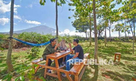 Pengunjung menikmati sajian kopi dengan latar belakang suasana Gunung Rinjani. Kopi Indonesia menarik bagi pasar internasional. 