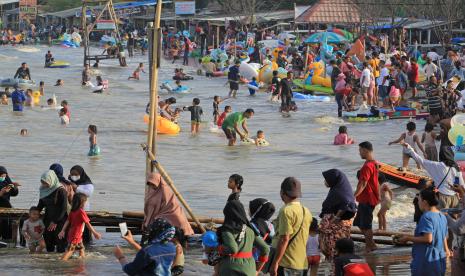 Pengunjung berwisata di kawasan Pantai Karangsong, Kabupaten Indramayu, Jumat (14/5/2021). 