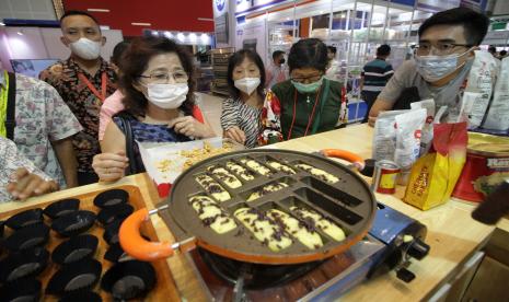 Pengunjung menyaksikan proses pembuatan kue pukis di salah satu stan pameran dalam Indonesia Food Exhibition 2022 di Surabaya, Jawa Timur, Jumat (10/6/2022). Pameran yang digelar hingga 12 Juni 2022 tersebut menampilkan berbagai teknologi dalam proses pembuatan serta pengolahan makanan dan minuman sekaligus sebagai ajang promosi bagi pelaku UMKM di bidang industri makanan, minuman serta produsen bahan baku pembuatannya. 