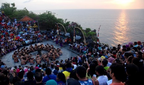 Pengunjung menyaksikkan pementasan Tari Kecak dari Sanggar Tari dan Tabuh Karang Boma di Pura Luhur Uluwatu, Bali.