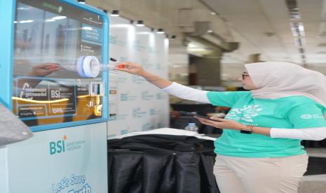 Pengunjung sedang memasukkan botol ke mesin RVM (reverse vending machine) pengolah botol plastik di BSI International Expo 2024. 