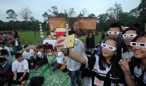 Pengunjung yang akan menyaksikan proses gerhana matahari total, berfoto dengan latar Candi Gumpung di Kompleks Percandian Muaro Jambi, Jambi, Rabu (9/3).