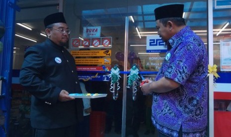 Pengurus Koperasi Syariah 212 Agus Siswanto menggunting pita sebagai tanda dibukanya gerai ke-8 212 Mart di Depok, didampingi Ketua Komunitas KS 212 Depok II, Muhammad Hidayatulloh (kiri), di Parung Bingung, Depok, Ahad (23/7).