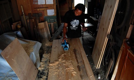 Pengusaha Usaha Kecil Menengah (UKM), Supri (30) menyerut papan pintu yang akan dijual di rumah produksi miliknya kawasan Lenteng Agung, Jakarta Selatan, Kamis (26/6). Dinas Koperasi Usaha Mikro Kecil dan Menengah (UMKM) meminta agar para pelaku UKM mening