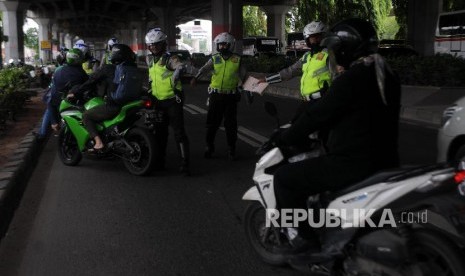 Polisi menghentikan pengendara motor yang melintas di jalur cepat saat melakukan Operasi Zebra di Jakarta Timur.