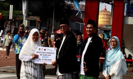 Penjabat (Pj) Wali Kota Sukabumi Kusmana Hartadji secara simbolis menyerahkan bantuan dari Baznas Kota Sukabumi untuk guru MDTA, TPQ, dan RA, saat kegiatan peringatan Hari Santri Nasional di Lapang Merdeka, Kota Sukabumi, Jawa Barat, Ahad (22/10/2023). 