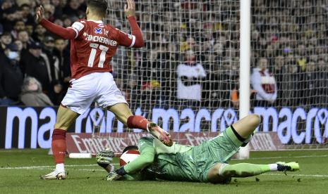 Penjaga gawang Arsenal Bernd Leno melakukan penyelamatan di depan pemain Nottingham Forest Philip Zinckernagel saat pertandingan sepak bola putaran ketiga Piala FA Inggris antara Nottingham Forest melawan Arsenal di City Ground, Nottingham, Inggris, Ahad 9 Januari 2022. 