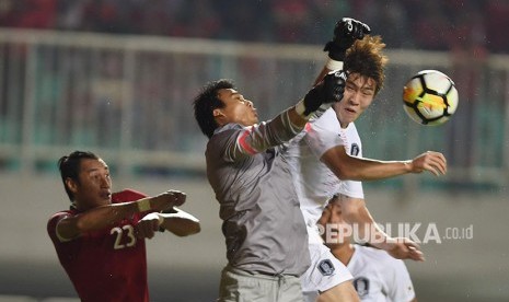 Penjaga Gawang Indonesia U-23 Muhammad Ridho (kiri) meninju bola mendahului tandukan pesepak bola korsel U-23 Hwang Yunsoo (kanan) dalam pertandingan ujicoba di Stadion Pakansari, Bogor, Sabtu (23/6). 