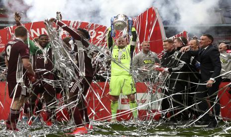 Penjaga gawang Leicester Kasper Schmeichel (tengah) mengangkat trofi saat rekan satu timnya merayakan kemenangan setelah memenangkan final Piala FA Inggris antara Chelsea FC dan Leicester City di Stadion Wembley di London, Inggris, 15 Mei 2021.