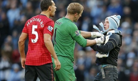  Penjaga gawang Manchester City Joe Hart mencegah pendukung Manchester City menghampiri pemain Manchester United Rio Ferdinand, setelah dihantam oleh sebuah benda yang dilemparkan dari arah penonton saat bertanding melawan Manchester City di Stadion Etihad