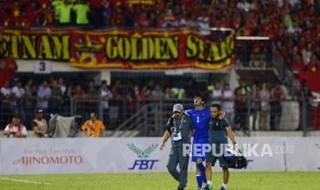 Penjaga gawang timnas Indonesia U-22 Satria Tama (tengah) dibantu tim medis meninggalkan lapangan akibat cedera saat melawan Vietnam.