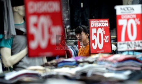 Penjaga menunggu pembeli di salah satu ritel penjualan pakaian di Pasar Baru, Jakarta Pusat, Senin (14/12).