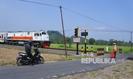 Penjaga perlintasan menghentikan kendaraan ketika sebuah kereta api melintas di perlintasan kereta api tanpa palang pintu di Desa Bedadung, Pakusari, Jember, Jawa Timur, Selasa (5/6). 