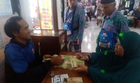 Penjaga stand jasa penukaran uang di embarkasi solo sibuk  melayani jamaah. Banyak jamaah menukarkan uang dengan pecahan 1 riyal untuk digunakan bersedekah saat tiba di tanah suci