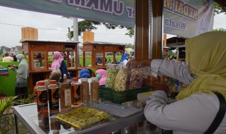 Penjual melayani pembeli saat pembukaan pusat penjualan hasil produk Usaha Mikro Kecil Menengah (UMKM), di Kelurahan Banjarejo, Kota Madiun, Jawa Timur, Sabtu (13/2/2021). 