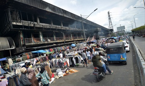 Penjual pakaian menggelar dagangannya di pinggir jalan pasca kebakaran yang melanda Pasar Senen, Jakarta Pusat, Senin (23/1). 