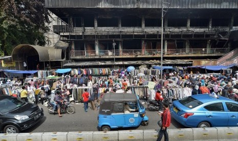 Penjual pakaian menggelar dagangannya di pinggir jalan pasca kebakaran yang melanda Pasar Senen, Jakarta Pusat, Senin (23/1).