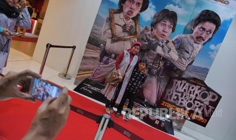 Penonton berfoto di poster Warkop DKI Reborn Part 1 pada acara BJB Wide Screen di Bekasi, Sabtu (10/9)