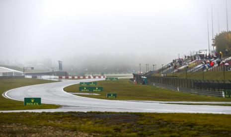 Penonton menanti di tribun saat turun hujan ketika start latihan bebas GP Eifel di Sirkuit Nuerburgring pada Jumat (9/10), ditunda. Latihan akhirnya dibatalkan karena cuaca yang kurang bersahabat untuk penerbangan medis antisipasi kecelakaan yang mungkin terjadi saat sesi ini.  